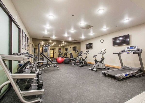 Un gimnasio con cintas de correr, elípticas y equipamiento de levantamiento de pesas.