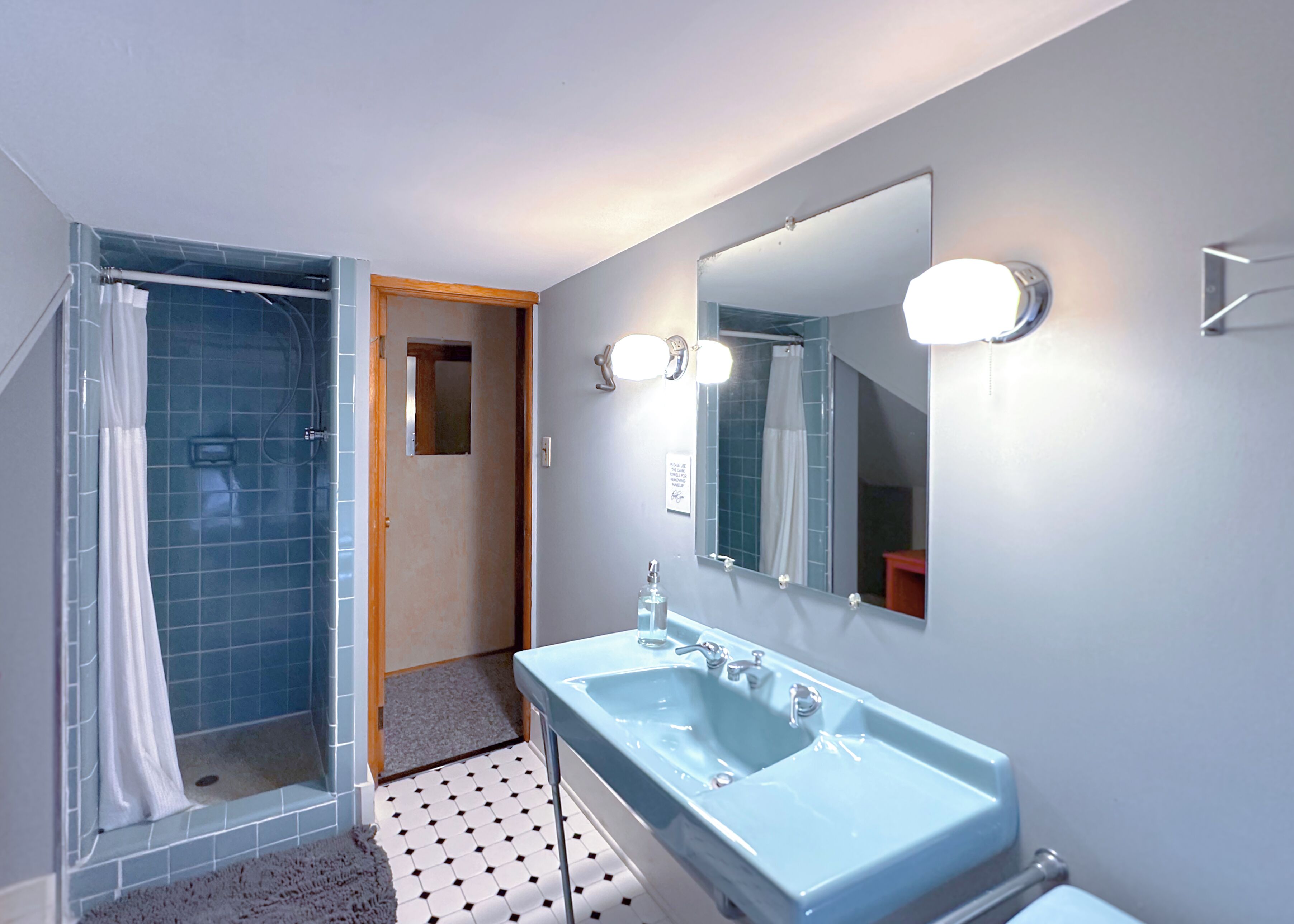 A bathroom with a shower, a sink, and a mirror.