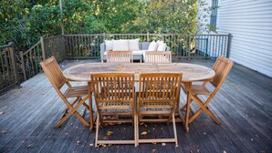A wooden deck with a round table and four chairs, a sofa with cushions, and a railing. - Charming estate on Norwich Green, near casinos (Norwich)