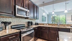 Una cocina moderna con armarios de madera oscura, electrodomésticos de acero inoxidable y encimera de granito.