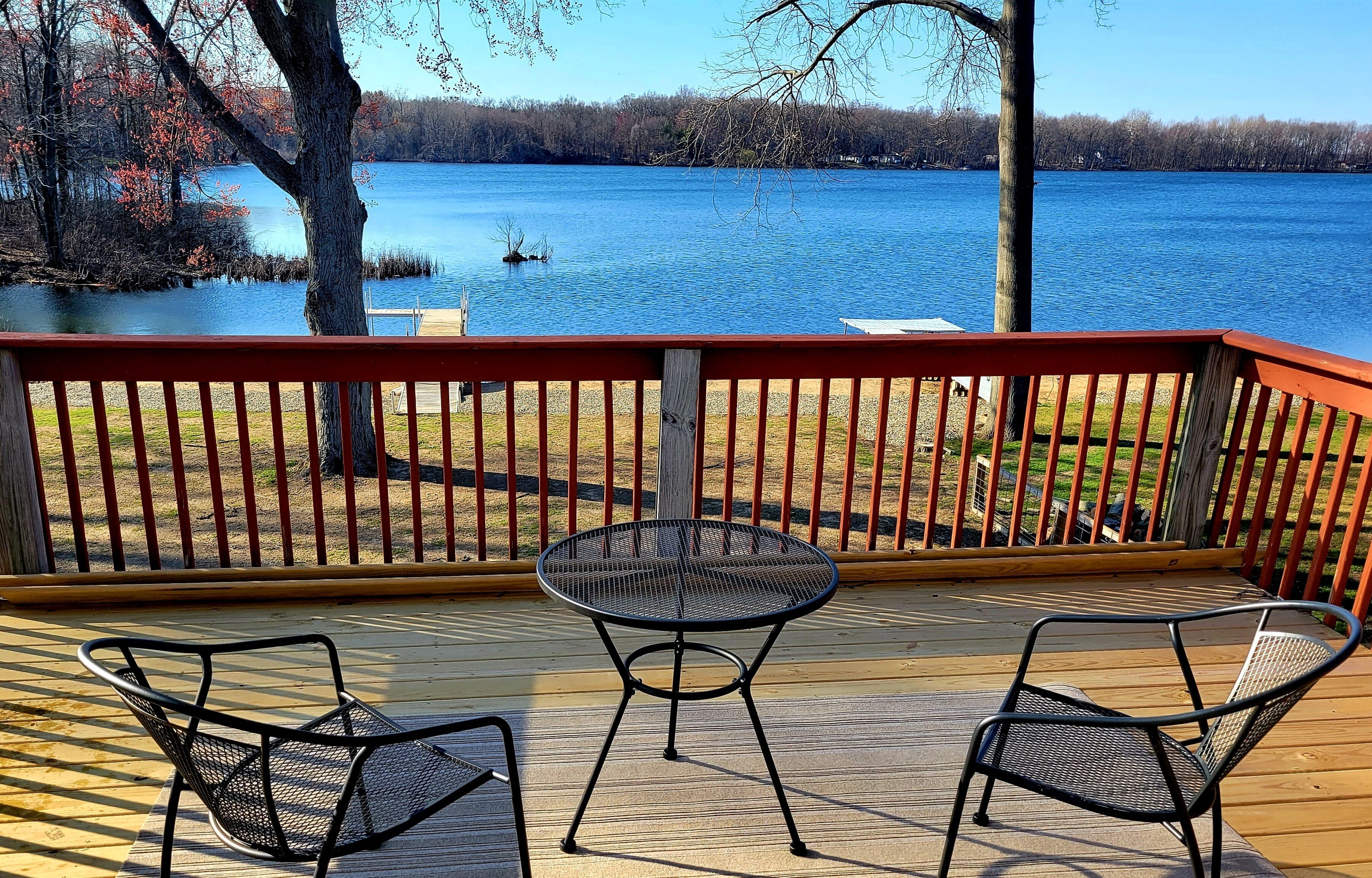 Une terrasse avec une table et deux chaises donnant sur un lac.