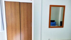 A room with a wooden wardrobe, a mirror on the wall, and a blue mat on the floor. - TC308 Aconchegante Studio na Praia (Rio de Janeiro)