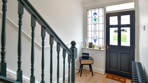 A staircase with dark wooden balusters, a black door with a window, and a small table with a laptop. - Just Stay Wales - Hadland House Mumbles (Swansea)