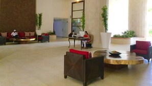 A spacious lobby with a large mirror, comfortable seating, and potted plants.