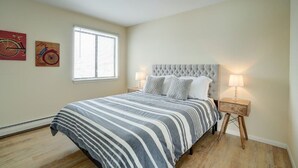 Un dormitorio con cama, ventana y dos lámparas fijadas a la pared.