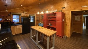 Cocina de cabaña de madera con una isla central, armarios de madera y un refrigerador.