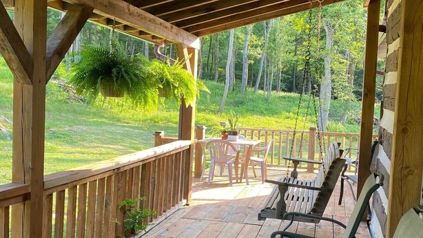 A wooden deck with outdoor furniture, including a table and chairs, and hanging plants.