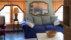 A cozy room with a blue sofa, a small table with a basket, and a fireplace.