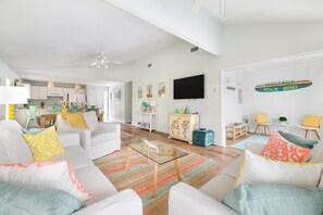 Relax in this inviting living space with a flat-screen TV, comfortable sofas, and a fully equipped kitchen area.