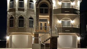A large, multi-story house with a central staircase, multiple balconies, and a garage. - Waterfront Luxury House on the Bay -  North Ocean City (Ocean City)