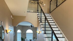 A spacious interior with a grand staircase, a dining area, and a hallway leading to a room with a large window. - Waterfront Luxury House on the Bay -  North Ocean City (Ocean City)
