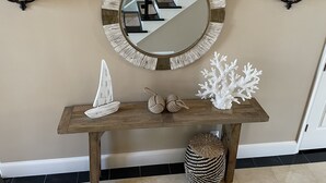 A wooden console table with a round mirror, a white coral sculpture, and a small sailboat model. - Waterfront Luxury House on the Bay -  North Ocean City (Ocean City)