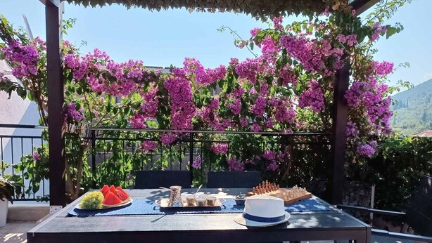 Un espace de restauration en plein air, avec une table dressée pour un repas, entouré de fleurs violettes et offrant une vue sur le paysage.
