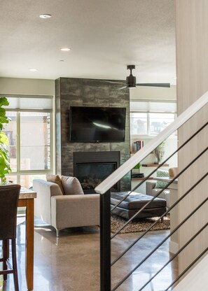 A modern living room with a fireplace, a flat-screen TV, and a staircase. - Swanky Townhome near Old Town, Breweries & River! (Fort Collins)