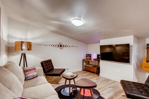 A modern living room with a sofa, two chairs, a coffee table, a TV, and a guitar. - Old Town Swank - Brand New To Brewery District! (Fort Collins)