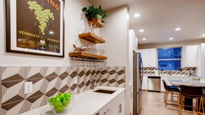 A modern kitchen with a white countertop, a bowl of green apples, a wine rack, and a potted plant. - Old Town Swank - Brand New To Brewery District! (Fort Collins)