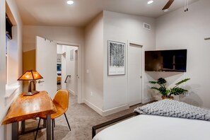 A modern bedroom with a bed, a desk with a chair, a TV, and a framed artwork on the wall. - Old Town Swank - Brand New To Brewery District! (Fort Collins)