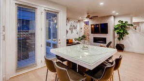 A modern dining area with a glass table, leather chairs, and a fireplace. - Old Town Swank - Brand New To Brewery District! (Fort Collins)