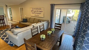 Ein gemütliches Wohnzimmer mit einem Holzesstisch, einer Couch und einem Deckenventilator.