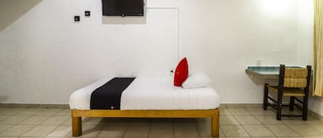 A single bed with a wooden frame, a small bedside table, a chair, and a wall-mounted TV.