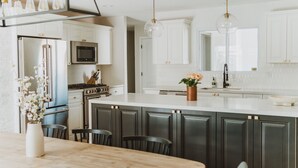 A modern kitchen with white cabinets, a large island, and pendant lighting. - *Great Rates Available* | Cactus Rose (Scottsdale)