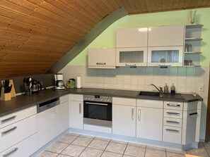 Eine moderne Küche mit weißen Schränken, einem eingebauten Ofen und einer Kaffeemaschine.