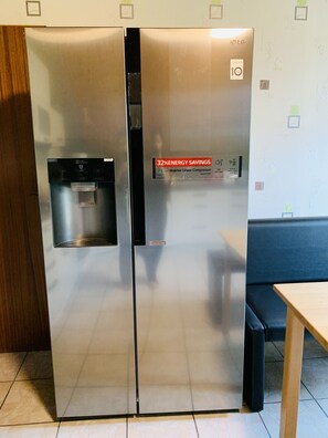 Ein Edelstahl-Kühlschrank mit Wasserspender und Kennzeichnung für 32% Energieeinsparung.