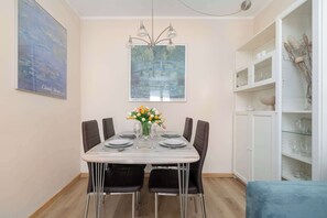 A dining area with a table set for four, a chandelier, and a painting above.