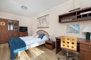 A bedroom with a bed, wooden wardrobe, desk, chair, and a world map on the wall.