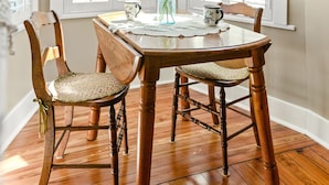 A dining area with a wooden table, two chairs, a vase with flowers, and a hanging light fixture. - Welcome to the Rusty Rose-Restored Farmhouse feel in the heart of Jefferson, MD (Jefferson)