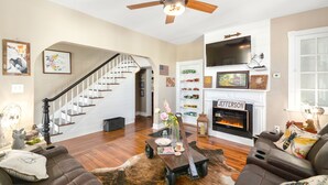 A living room with a fireplace, a television, a staircase, and a bookshelf. - Welcome to the Rusty Rose-Restored Farmhouse feel in the heart of Jefferson, MD (Jefferson)