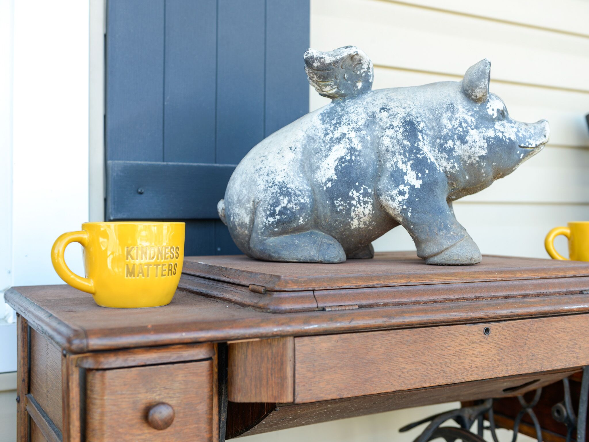 A rustic wooden desk with a pig-shaped sculpture and a yellow mug with text.