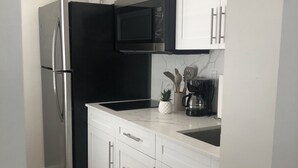 Eine moderne Küche mit weißen Schränken, einem Edelstahlkühlschrank, einer Mikrowelle und einem Spülbecken.