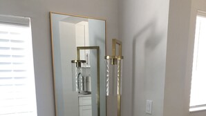 Ein modernes Zimmer mit einem großen Spiegel, einem runden Hocker und einem kleinen Schemel.
