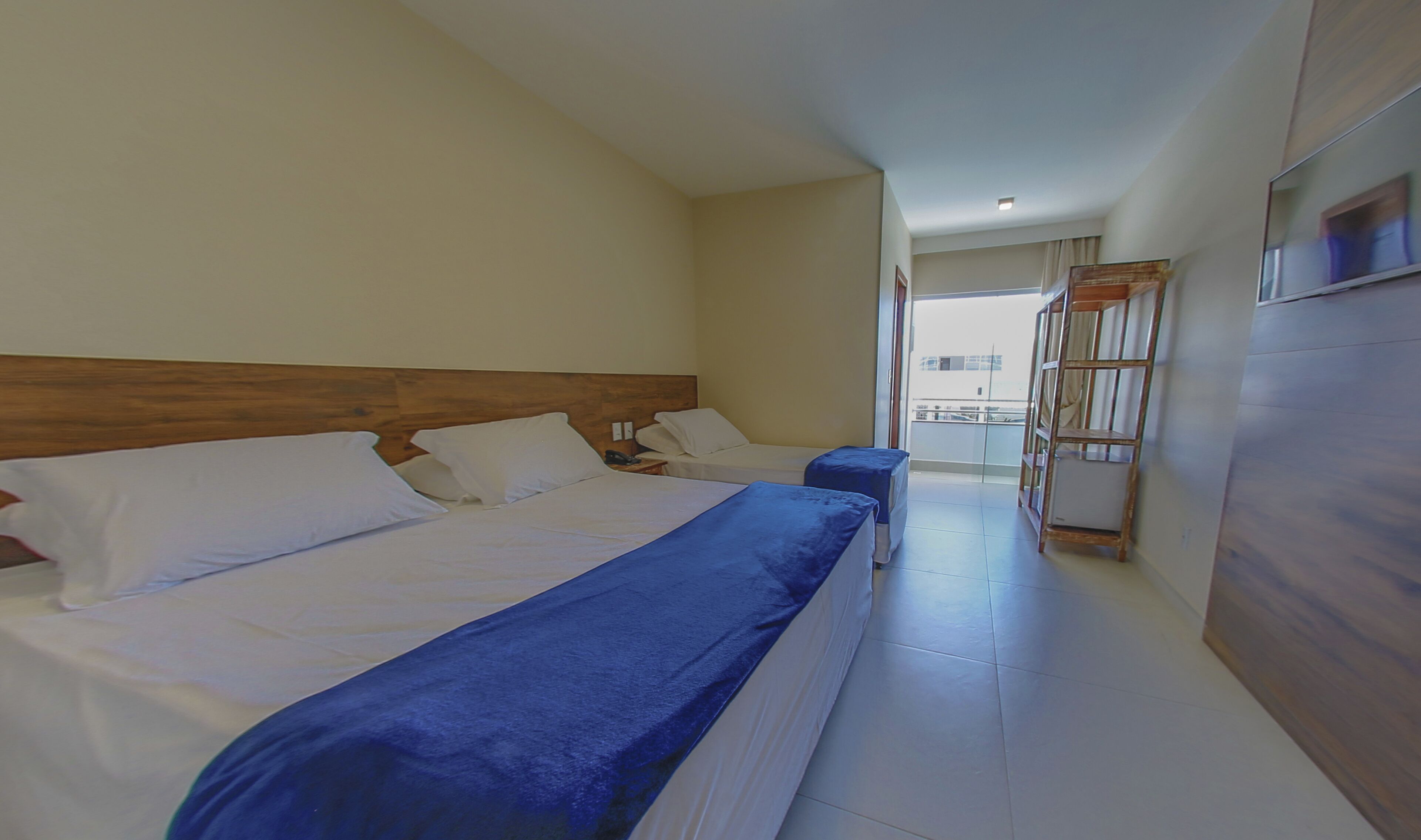 Une chambre d’hôtel avec deux lits, une tête de lit en bois, un balcon avec vue et un téléviseur fixé au mur.