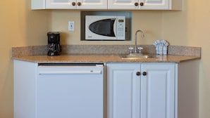 A compact kitchen with a microwave, coffee maker, and a sink.