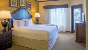 A hotel room with a double bed, two bedside tables with lamps, a dresser, and a large window with curtains. - GRANDE VILLAS AT WORLD GOLF VILLAGE (St. Augustine)