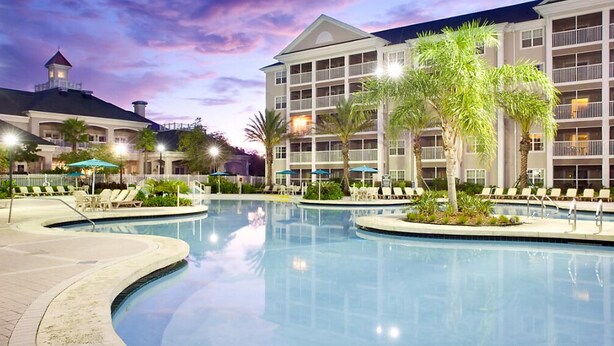 A hotel with a large outdoor pool, lounge chairs, and palm trees. - GRANDE VILLAS AT WORLD GOLF VILLAGE (St. Augustine)