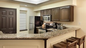 A kitchen with granite countertops, stainless steel appliances, wooden cabinets, and a built-in microwave. - GRANDE VILLAS AT WORLD GOLF VILLAGE (St. Augustine)