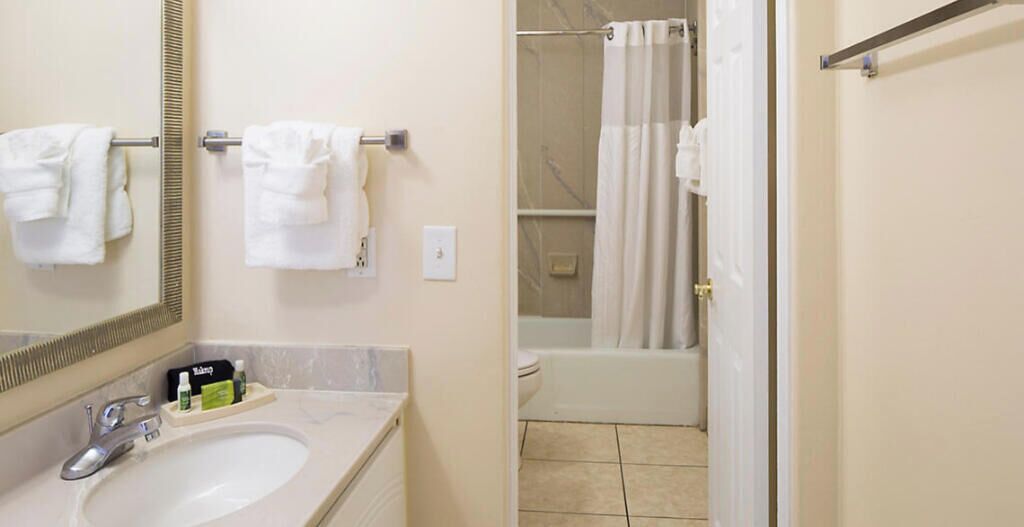 Une salle de bain équipée d’un lavabo, d’un miroir, d’un porte-serviettes et d’une zone douche.