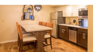 A compact kitchen with a dining table, chairs, a refrigerator, a microwave, and a dishwasher. - CASA DEL MAR BEACH RESORT (Ormond Beach)