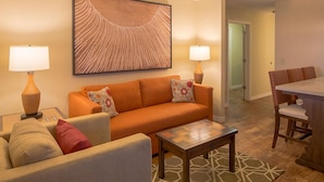 A living room with a sofa, two armchairs, a coffee table, and a dining area with a table and chairs. - CASA DEL MAR BEACH RESORT (Ormond Beach)