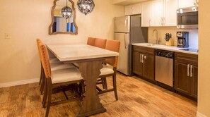 A compact kitchen with a dining table, chairs, a refrigerator, a microwave, and a dishwasher.