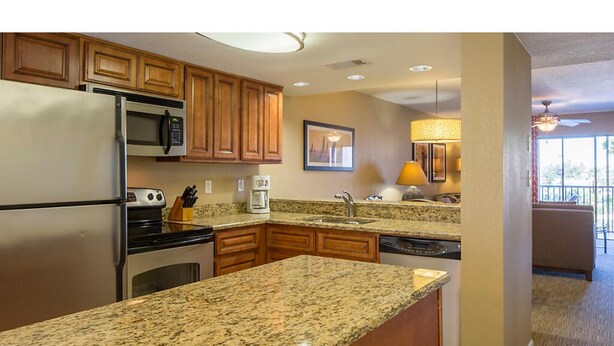 Una cocina moderna con encimeras de granito, armarios de madera y electrodomésticos de acero inoxidable, además de un comedor con vistas.