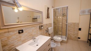A bathroom with a sink, toilet, and glass-enclosed shower. - Dolci Emozioni Room 82 (Bari)