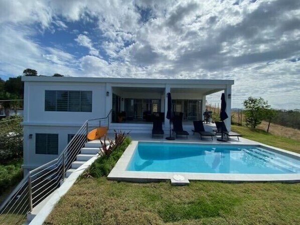 A modern two-story house with a swimming pool, outdoor seating, and a staircase leading to the upper level. - The Ranch At La Joya is a three bedroom modern farm house at Tres Palmas Estates (Rincón)