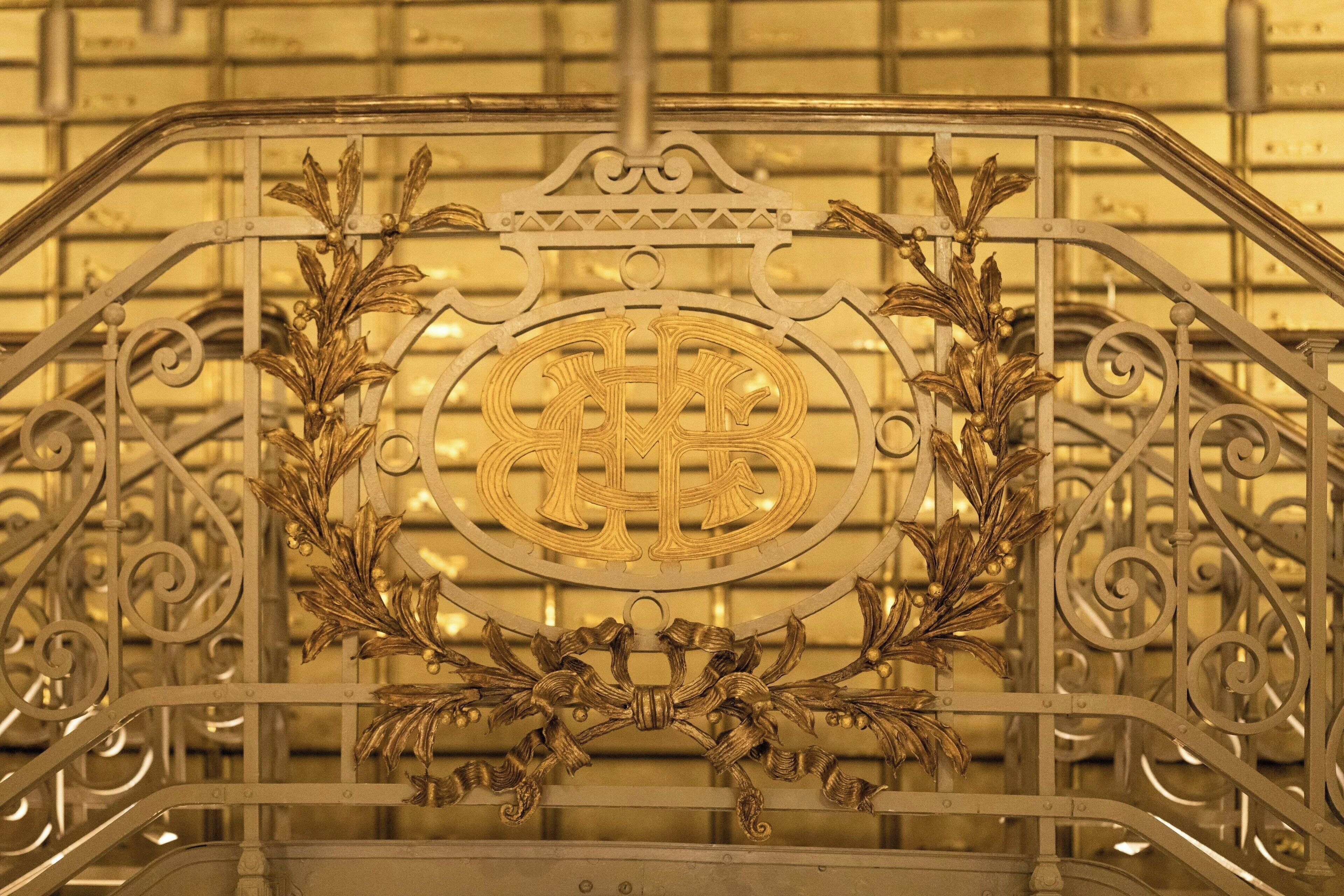 Una escalera metálica con barandillas ornamentales y un emblema central.