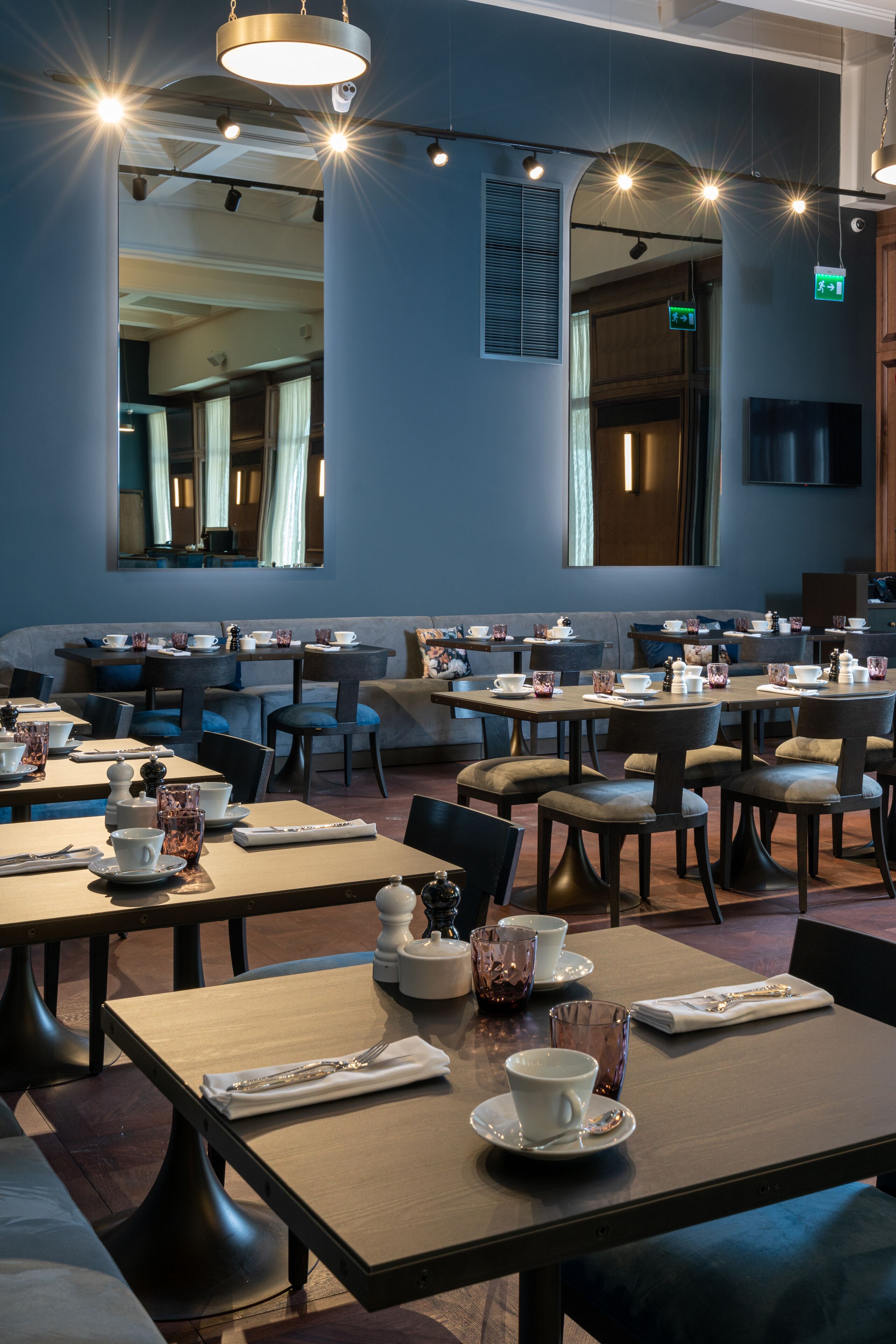 A modern dining area with multiple tables and chairs, equipped with tea sets and cups.
