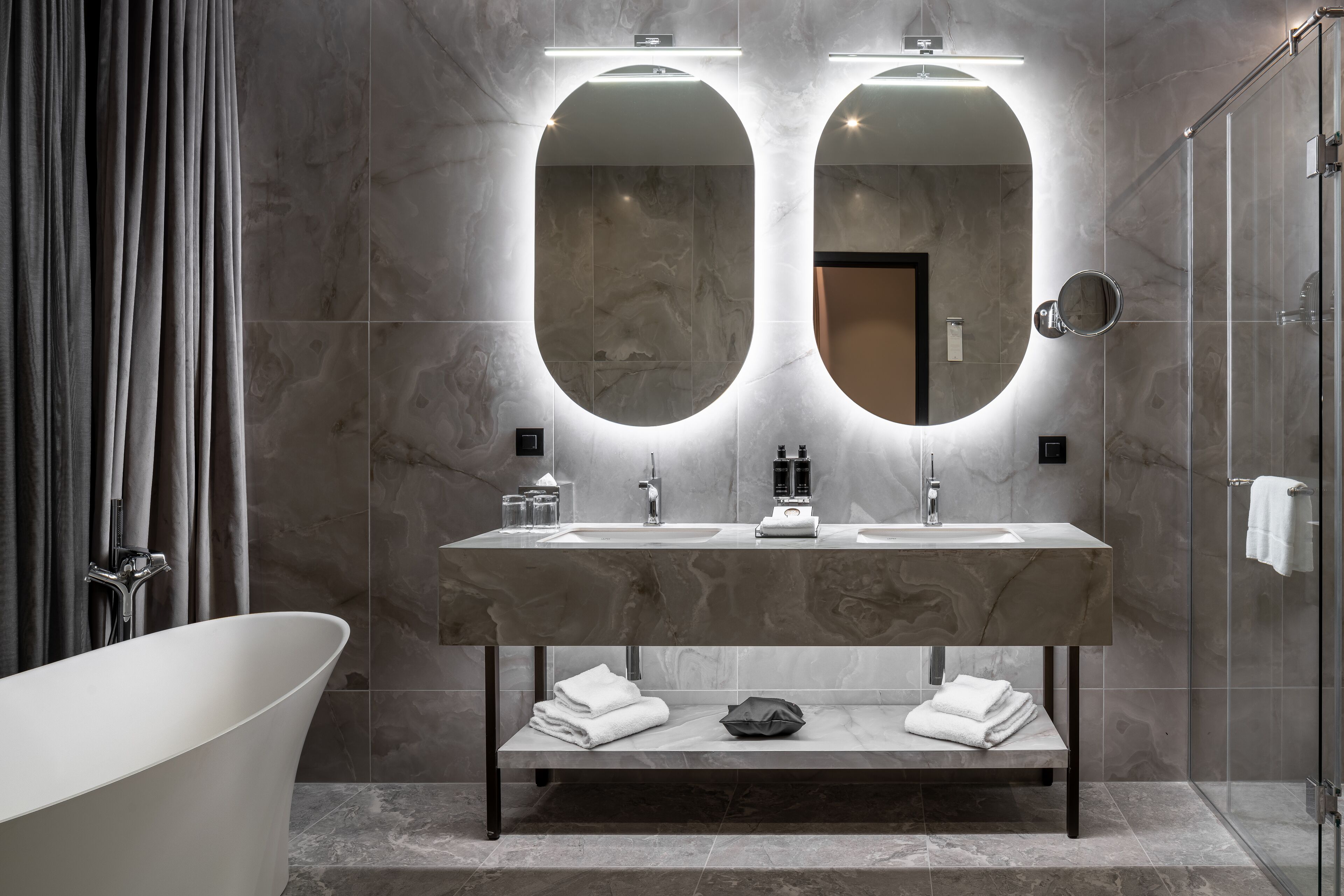 A modern bathroom with a freestanding bathtub, a double sink vanity, and a large mirror.