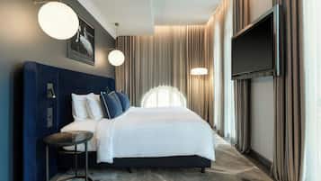 Una habitación de hotel moderna con una cama grande, un televisor de pantalla plana y una mesa redonda.